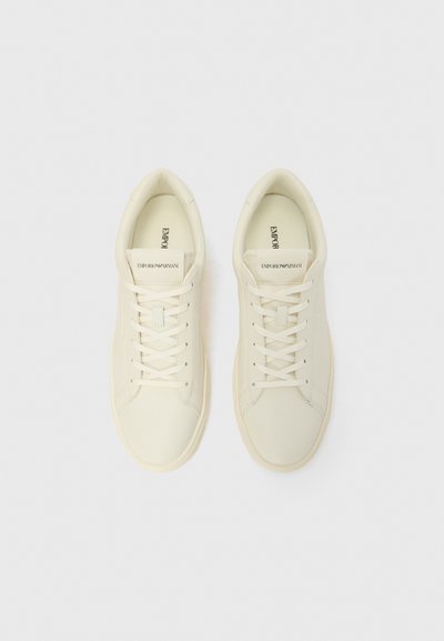 Ténis creme com acabamento em couro liso, formato de biqueira redonda, atacadores texturizados e um logótipo subtil na língua.
