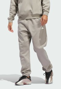 Grauer Baumwollmischung-Sweatshirt und Sweathose, mit geripptem Taillenbund und Bündchen, kombiniert mit schwarzen und pinken Sportschuhen.