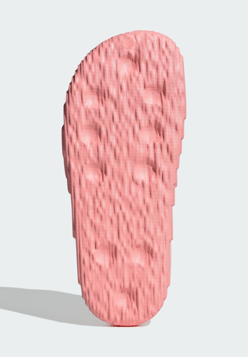 Semelle de sandale en caoutchouc rose avec des rainures texturées et des points en motif pour une meilleure adhérence. Forme arrondie avec une finition lisse.