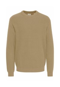 Beige ribbed sweater with a crew neck, long sleeves, and fitted cuffs. Soft texture with a relaxed silhouette and a label visible at the neck.