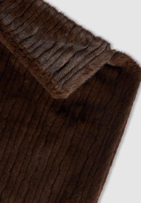 Tessuto in pelliccia sintetica marrone con superficie strutturata, caratterizzato da un bordo superiore liscio e soffice e da scanalature verticali per un effetto tridimensionale.