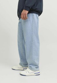 Jeans din denim de un albastru deschis, cu o croială lejeră, având un design cu picioare drepte. Asortați cu adidași albi cu accente bleu și panouri texturate.