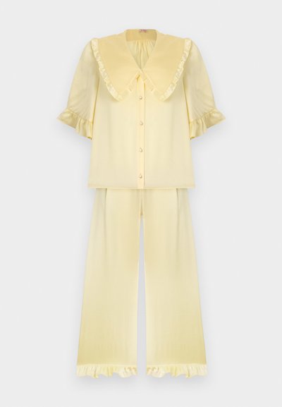 Ensemble pyjama deux pièces jaune clair avec grand col à volants, manches courtes bouffantes, haut boutonné et pantalon large avec ourlets à volants.