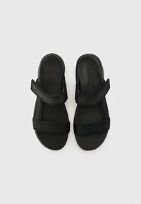 Black sandals with two adjustable straps, flat sole, and a cushioned footbed. Material appears synthetic and smooth.