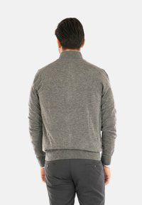 Giacca bomber grigia lavorata a maglia con colletto alto, orlo e polsini a costine, mostrata da dietro. Tessuto morbido, design aderente e dettagli minimi.
