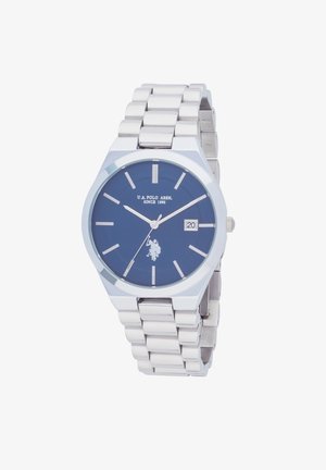 Montre en acier inoxydable argenté avec un cadran bleu, des index argentés et un affichage de la date. Présente un logo de joueur de polo. Forme ronde classique.