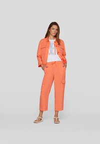 Coral-colored, lightweight two-piece outfit featuring a cropped jacket with pockets and loose-fitting cargo pants with an elastic waistband.