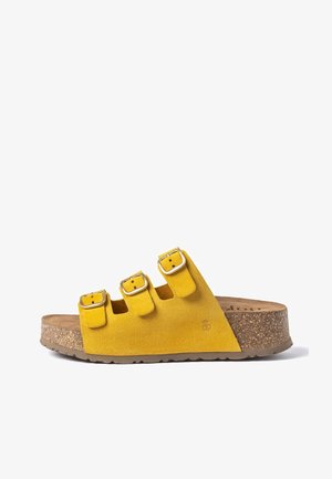Yellow suede sandal with three adjustable buckled straps and cork platform sole.