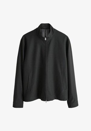 Fekete cipzáras dzseki álló gallérral, két oldalzsebbel és sima, matt textúrával. Egyszerű kialakítás és egyenes szabású sziluett.