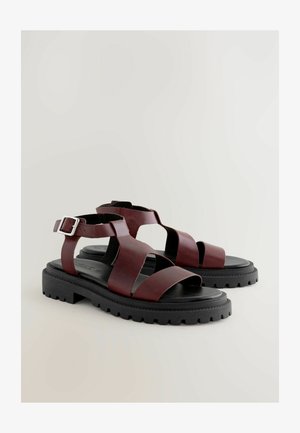 Bordové sandále s širokými koženými popruhmi, otvorenou špičkou, nastaviteľnou prackou na členku a robustnou čiernou gumovou podrážkou s textúrovaným vzorom.