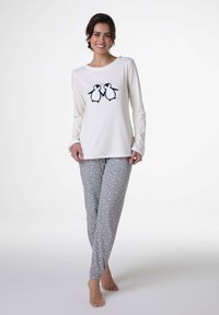 Maglia a maniche lunghe color crema con grafica di pinguino, abbinata a pantaloni da pigiama grigi con stampa multicolore vivace e polsini elastici.