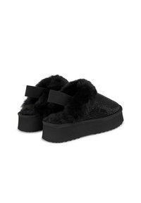 Zwarte instapschoenen hebben een getextureerde bovenkant, een zachte nepbontvoering, elastische bandjes en een dikke zool met een gestippeld profiel voor grip.