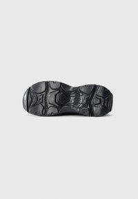 Semelle de chaussure en caoutchouc noir présentant des motifs texturés et des nervures, conçue pour une traction avec un talon défini et une structure de semelle intermédiaire flexible.