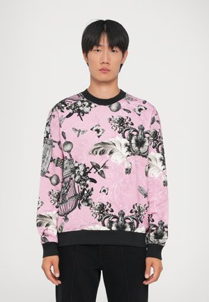 Lyserød sweatshirt med sorte grafiske blomster- og sommerfuglmønstre, ribbede sorte manchetter og halsudskæring. Har en afslappet pasform og blød tekstur.