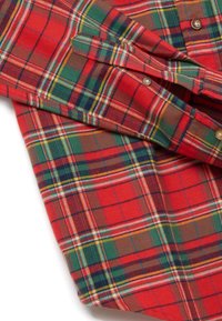 Camicia a quadri rossa con accenti verdi, gialli e blu. Il tessuto ha una texture morbida con chiusure con bottoni e dettaglio di polsini piegati.