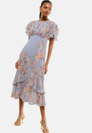 Light blue floral midi dress with ruffle sleeves and layers, featuring a keyhole neckline and a flowing silhouette. Gold strappy sandals.