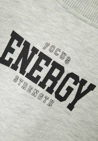 Gray cotton sweatshirt featuring bold black text reading "ENERGY" with smaller text "FOCUS" and "STRENGTH" below in contrasting fonts.