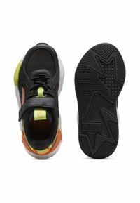 Baskets noires de sport avec une tige en maille, accents verts et orange, sangle ajustable et semelle en caoutchouc texturé avec un motif de grip.