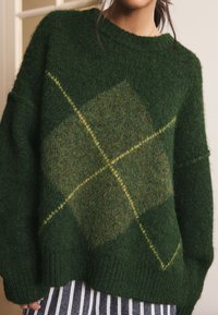 Green knitted sweater with a fuzzy texture, featuring a large diamond pattern in lighter green and yellow stitching. Long sleeves and ribbed hem.