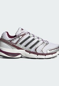 Chaussure de course Adidas blanche et marron avec dessus en mesh, semelle en caoutchouc, talon rembourré et trois bandes latérales noires.