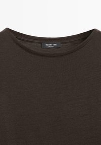 Brązowy, dziergany t-shirt z krótkim rękawem i okrągłym dekoltem. Posiada metkę z napisem "Massimo Dutti". Materiał wydaje się miękki i o fakturze.