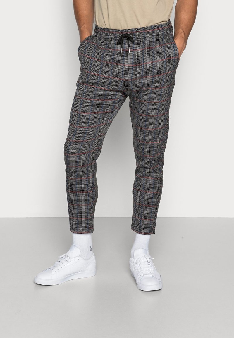 Pantalons à carreaux gris avec une taille à cordon, présentant un motif écossais rouge et bleu subtil. Coupe ajustée avec des poches latérales.