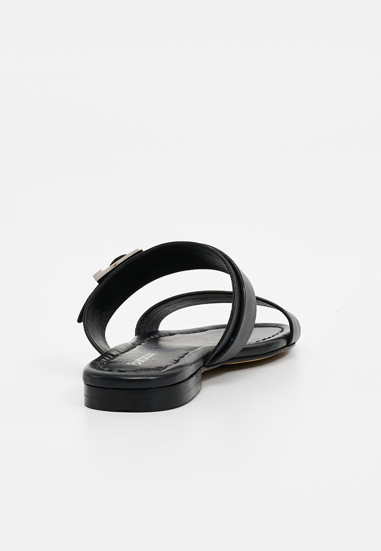 Czarne skórzane sandały z dwiema zakrzywionymi paskami, płaską podeszwą i srebrnym akcentem w okolicy kostki. Gładka tekstura, minimalistyczny design.