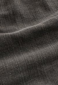 Tissu gris foncé avec une texture douce et tissée, et des ombres subtiles mettant en valeur les plis délicats du matériau.