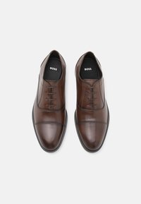 Pantofi de dress din piele maro cu un finisaj neted, design cu șireturi, vârf rotund și accente subtile de cusătură. Inscripționat cu "BOSS" pe branț.