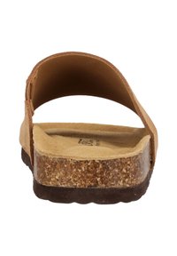 Sandale marron avec une bride supérieure incurvée et une semelle en liège. La semelle intérieure est texturée et d'un beige clair, contrastant avec la semelle extérieure marron foncé.