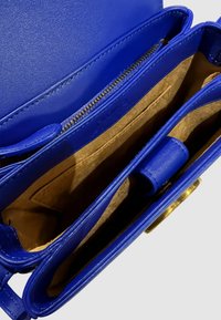Interno di una borsa a tracolla blu in pelle con foderatura in suede color beige, presenta un compartimento con zip e tasche aggiuntive per l'organizzazione.