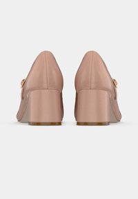 Pantofi roz din satin cu toc gros, vârf ascuțit, având un mic accesoriu sub formă de fundă și textură netedă. Baza tocului este solidă, ușor transparentă.