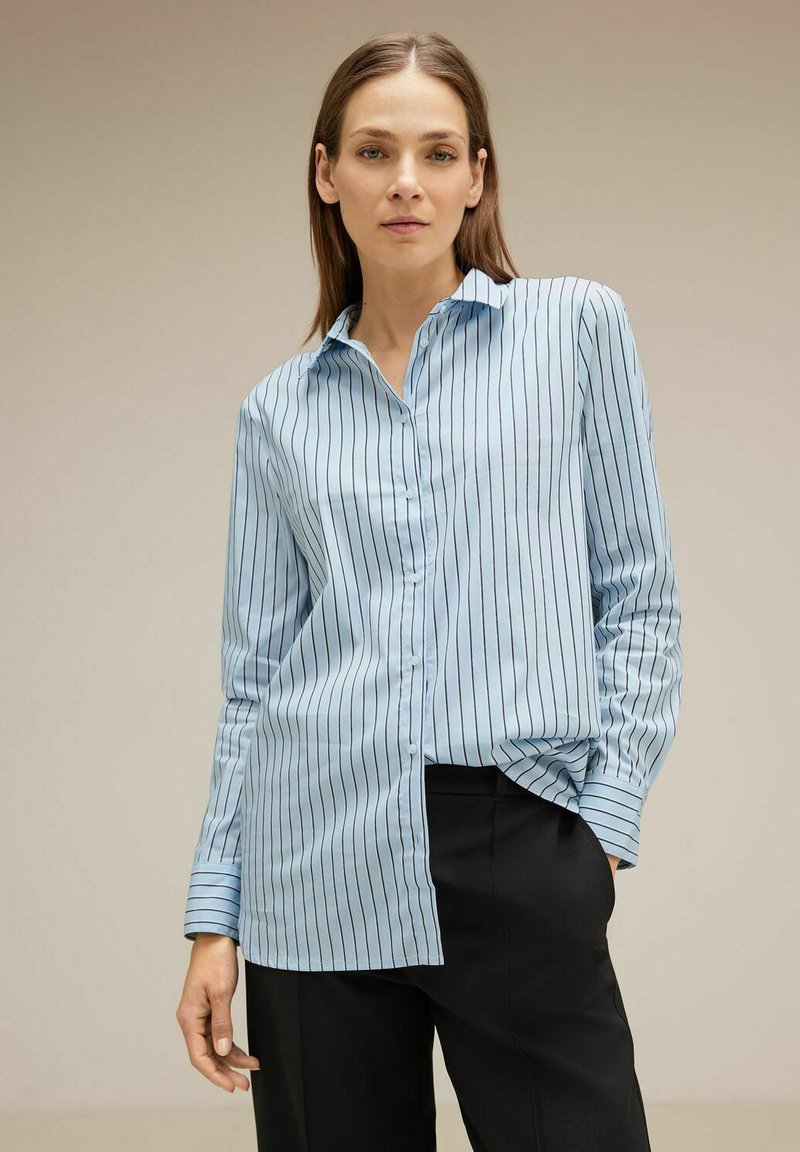 Light blue button-up shirt with vertical black stripes, long sleeves, and a pointed collar; fabric appears smooth and slightly shiny.