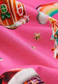 Tessuto rosa con una consistenza morbida, caratterizzato da stampe colorate di case di pan di zenzero, stelle e un arcobaleno.