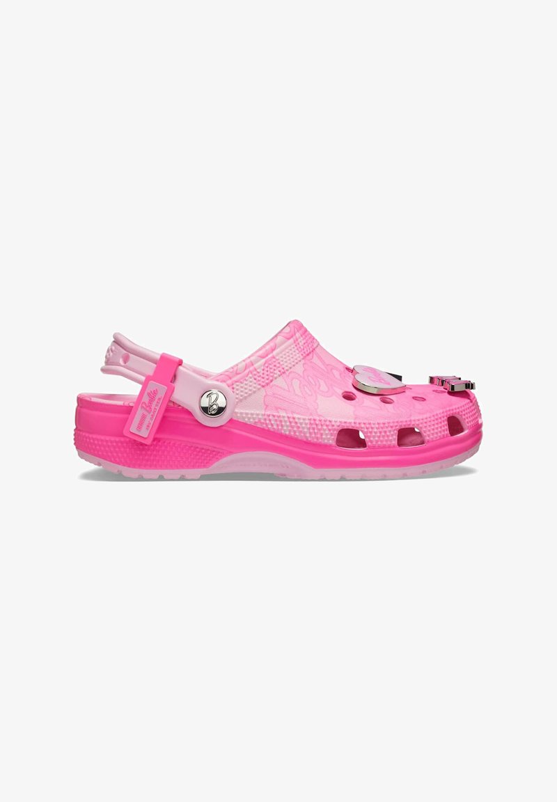 Sabot en plastique rose avec un design ouvert, comportant des trous de ventilation, une sangle de talon réglable et des charms décoratifs sur le dessus.
