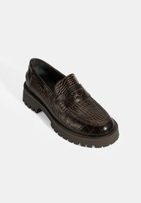 Bruine leren loafers met een krokodillenstructuur, een dikke grijze rubberen zool en een detailbandje aan de voorkant. Glad afgewerkt met gedetailleerde stiksels.