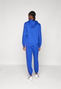 adidas Sportswear ESSENTIALS 3 STRIPES ANIMAL PRINT 7/8 PANT - Tracksuit bottoms - semi lucid blue/multicolor