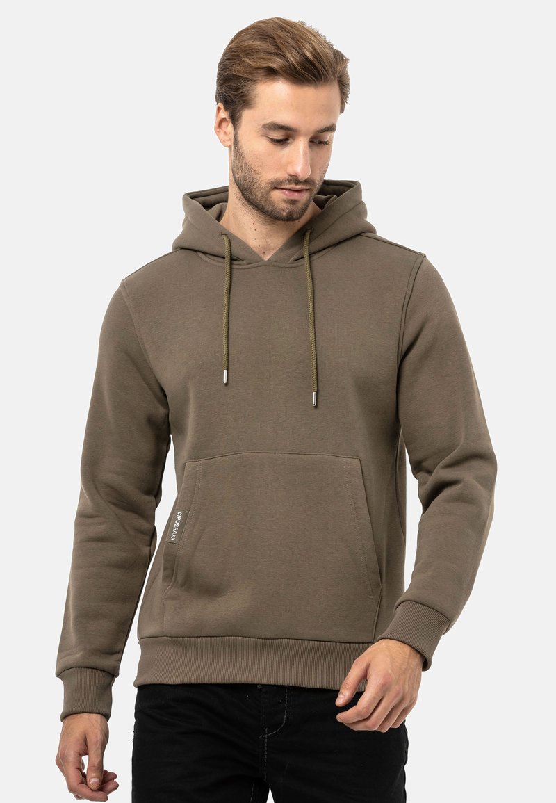 Olivgrüner Kapuzenpullover mit einer Fronttasche und Kordelzügen. Hergestellt aus glattem, strukturiertem Stoff mit gerippten Bündchen.