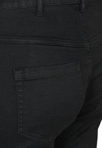 Pantalones de mezclilla negros con un bolsillo trasero, presentan costuras reforzadas y una textura suave y elegante. Simples, sin adornos ni patrones.