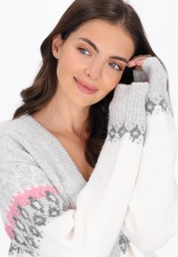 Graue und weiße Strickjacke mit pinken Akzenten; V-Ausschnitt, gerippte Bündchen und eine weiche Textur; mit geometrischem Muster an den Ärmeln.