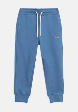 Pantaloni della tuta blu con vita elastica, coulisse bianche, tasche laterali, polsini a coste sulle caviglie e piccolo logo ricamato sulla coscia sinistra.