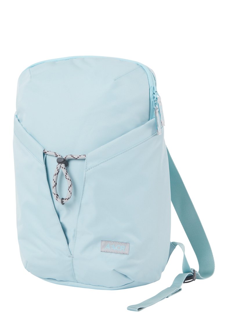 Mochila de color azul claro con un bolsillo frontal con cremallera, correa ajustable y un lazo de cordón gris en el bolsillo frontal.