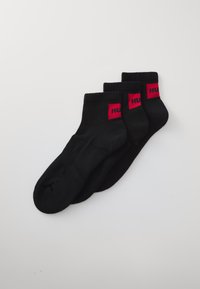 Zwarte enkelkousen met een geribbelde boord en rode logo-accenten. Gemaakt van een zachte, rekbare stof, ontworpen voor comfort en pasvorm.