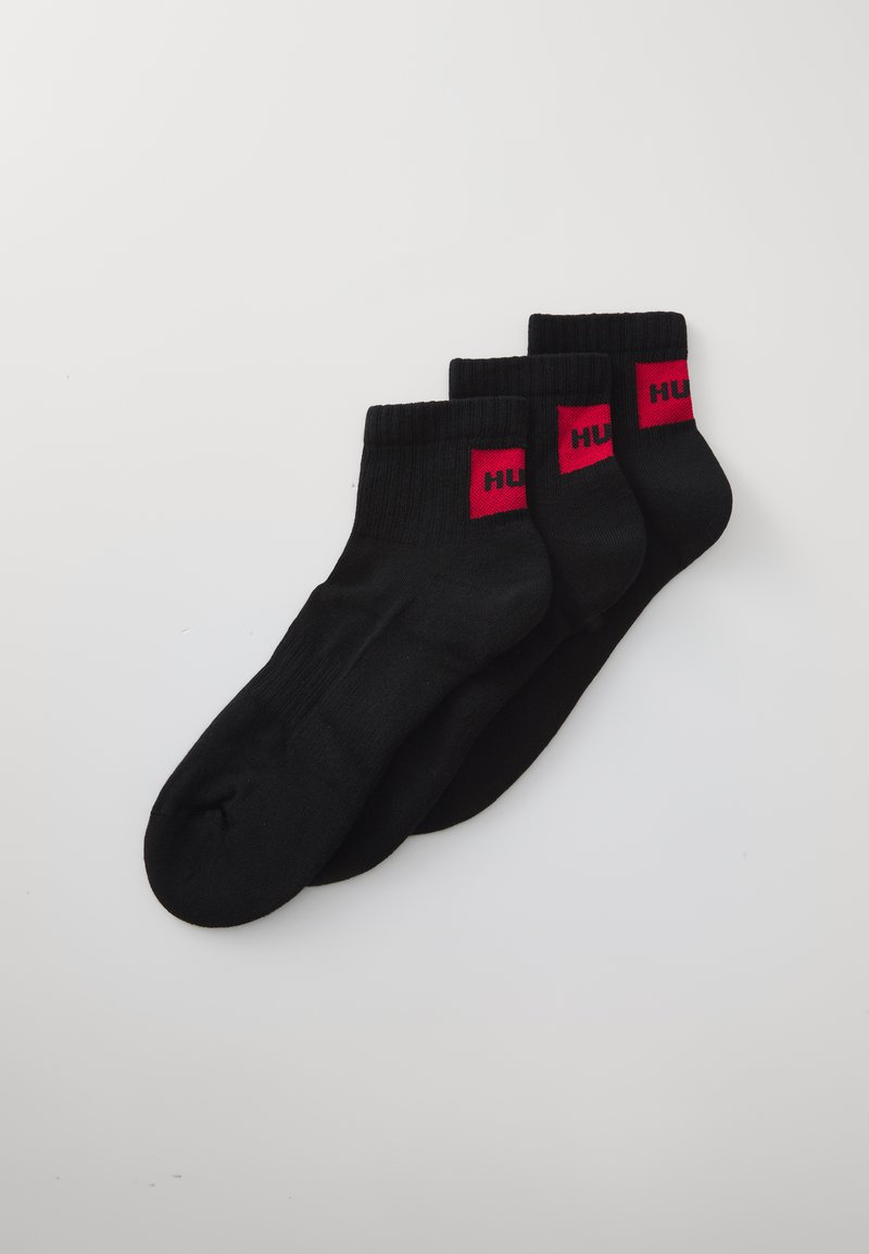 Zwarte enkelkousen met een geribbelde boord en rode logo-accenten. Gemaakt van een zachte, rekbare stof, ontworpen voor comfort en pasvorm.