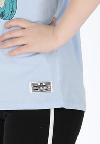 Light blue t-shirt made of cotton with a graphic design. Features a "DENIM FACTORY" tag at the bottom and a relaxed fit.