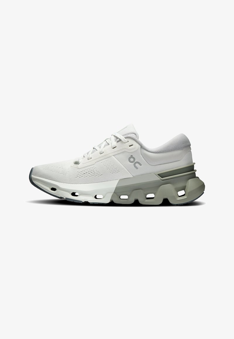 Zapatilla deportiva blanca con parte superior de tela de malla, cordones y cuello acolchado. Cuenta con una suela gris con recortes para amortiguación y flexibilidad.