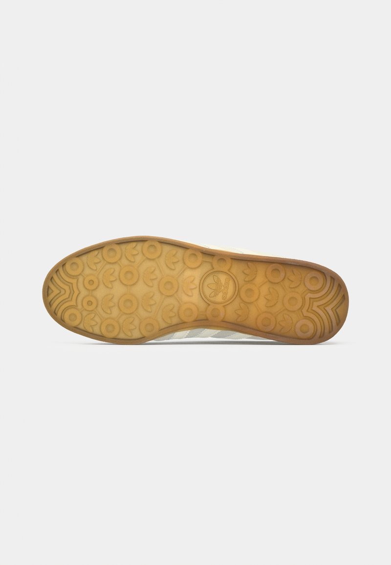 Rubber shoe sole with a textured, patterned design; light brown color with circular grips and brand logo embossed in the center.