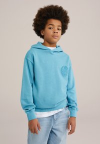 Hanorac de culoare albastru deschis, cu un logo țesut pe piept, având glugă cu șnur și manșete ribbd. Asortat cu blugi din denim deschis.