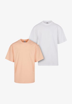 Två kortärmade t-shirts: en i mjuk persika och den andra i vitt. Båda har en rund halsringning och är gjorda av ett mjukt, lätt material.