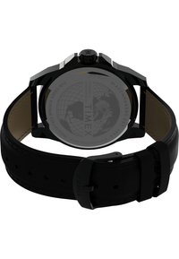 Montre-bracelet en cuir noir avec un fond en acier inoxydable, un boîtier rond et un bracelet texturé. Présente une couronne proéminente et des détails gravés.